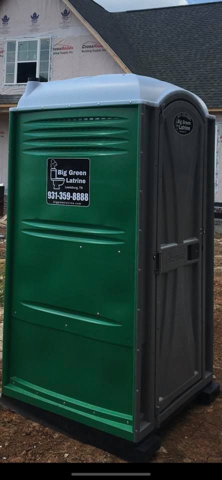 Green portable toilet outside a house with a black sign on the door