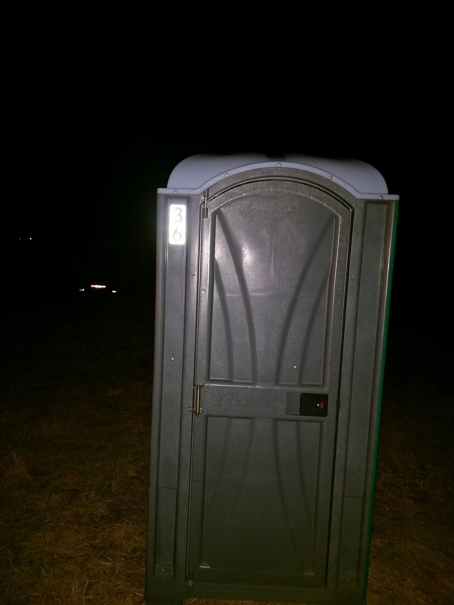 Portable toilet on a dark outdoor field at night.