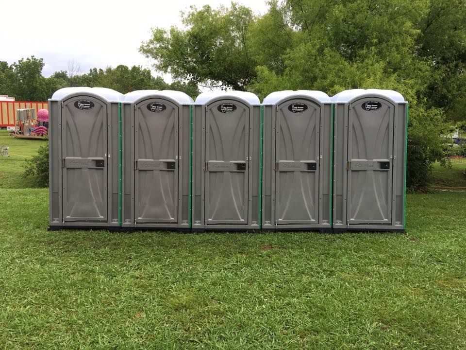Row of gray portable toilets on grass at an outdoor event site