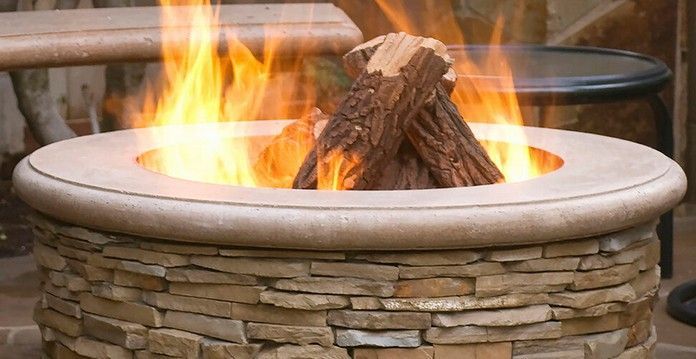Fire pit with burning logs, flames, and a stone exterior.