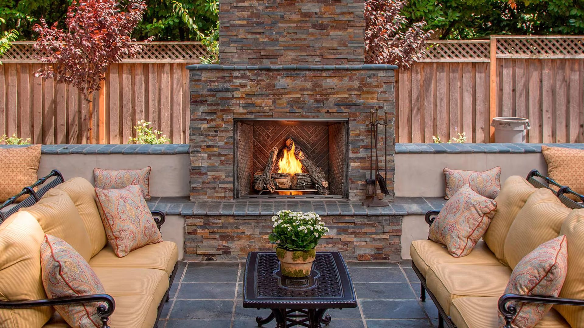 Outdoor patio with a stone fireplace, couches, and a table.