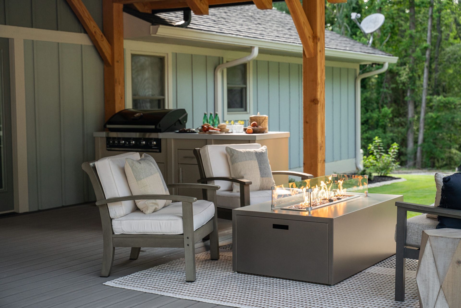 Outdoor patio with seating, fire pit, grill, and covered area, light gray and wooden tones.