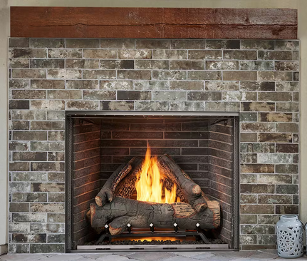 Fireplace with burning logs, brick surround, and wooden mantel.