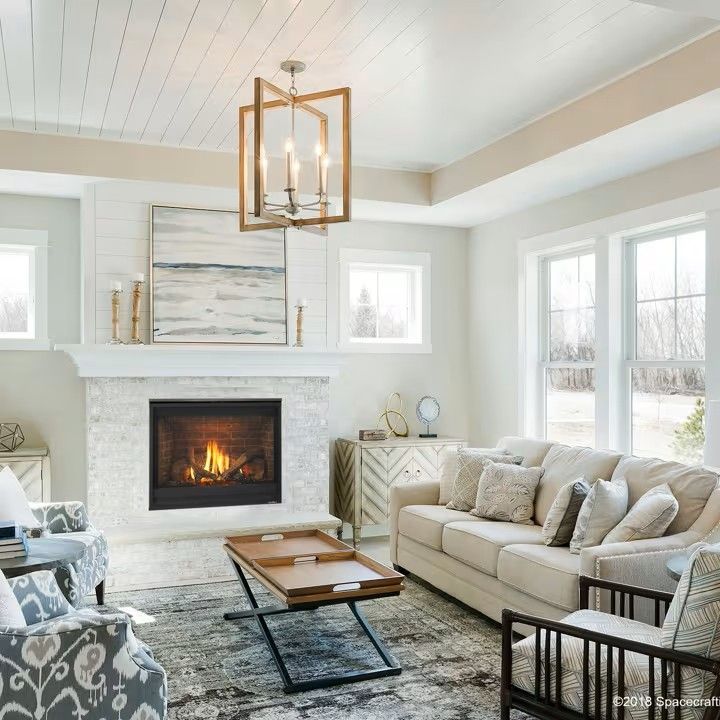 Cozy living room with fireplace, neutral colors, white walls, wood accents, chandelier, sofa, and chairs.