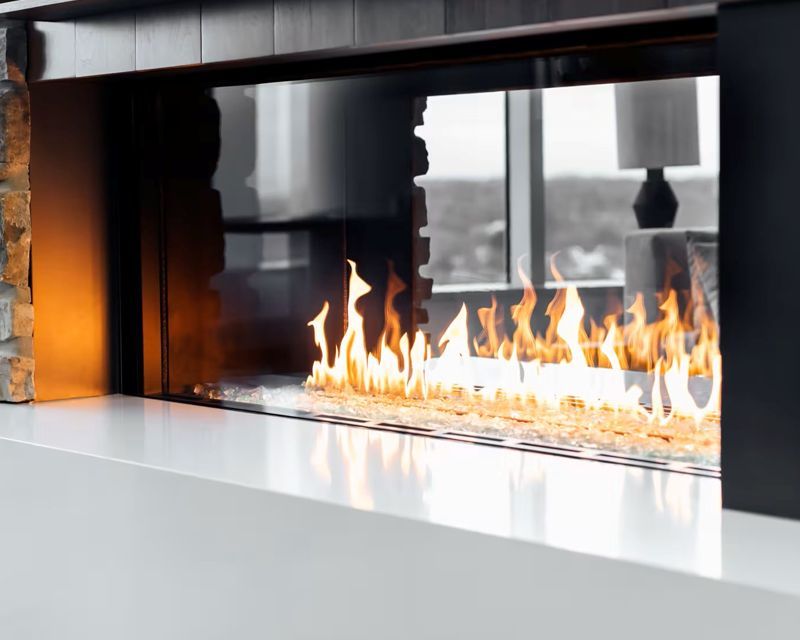 A modern fireplace with flames behind glass, set in a white and dark-trimmed surround.