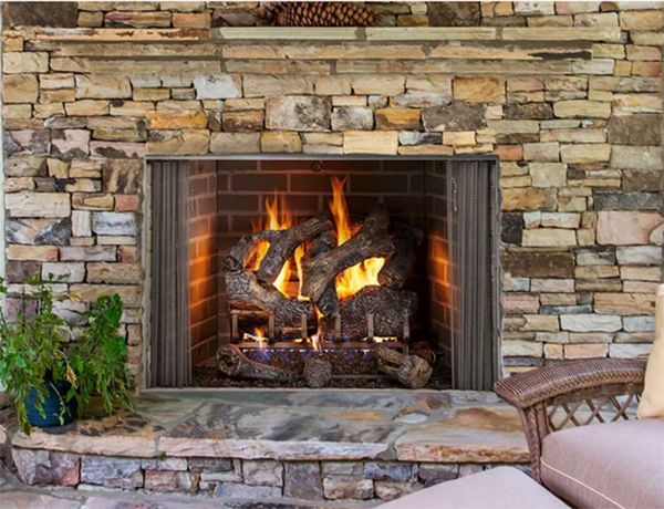 Fireplace with burning logs in a stone-lined setting; flame's warm glow illuminates the brick interior.