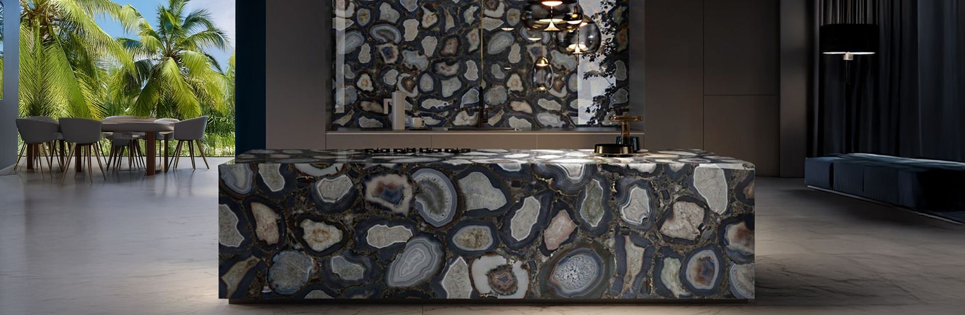 A modern kitchen with a large dark stone countertop. Tropical trees are visible outside the window.