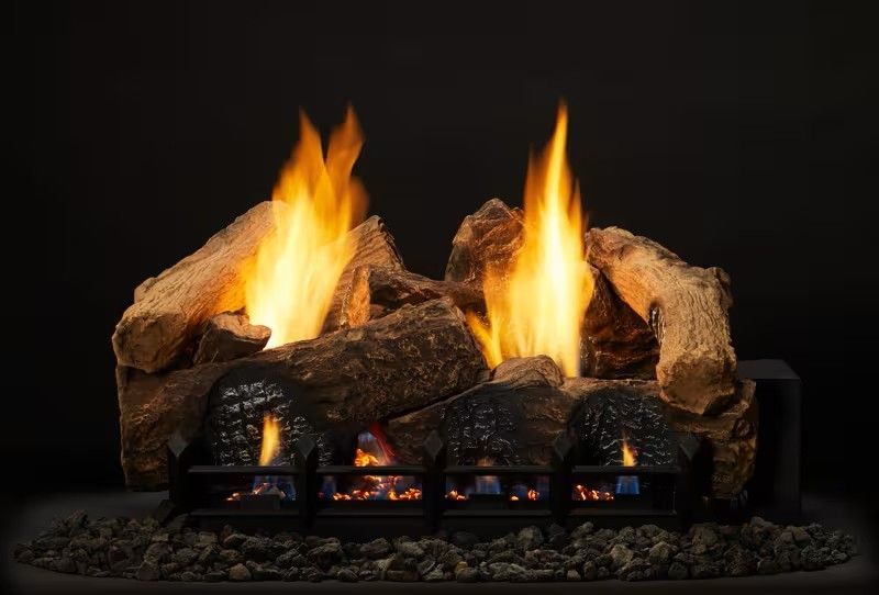 Gas fireplace with burning logs and flames against a dark background.