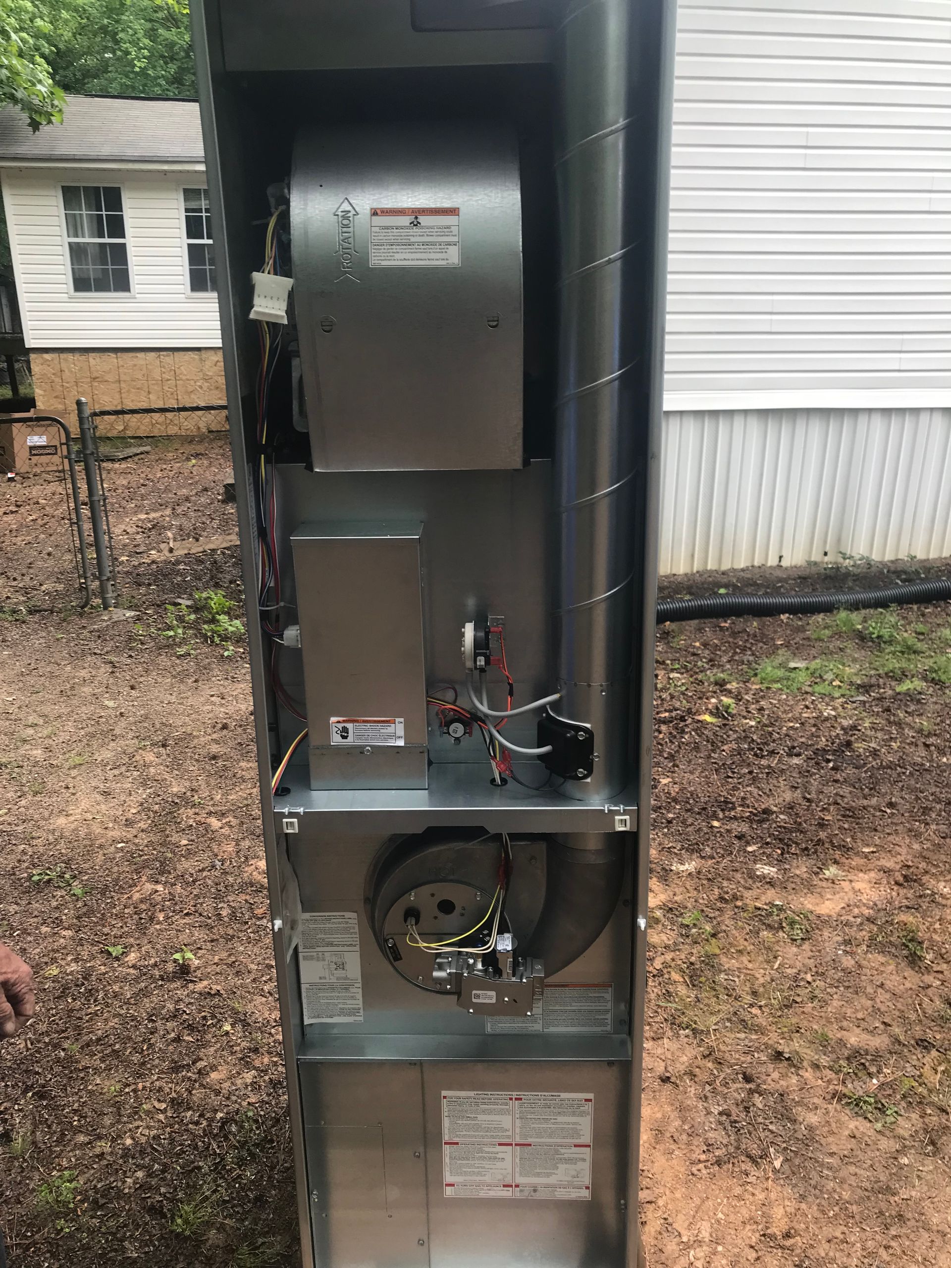 A stainless steel air conditioner is sitting outside of a house.