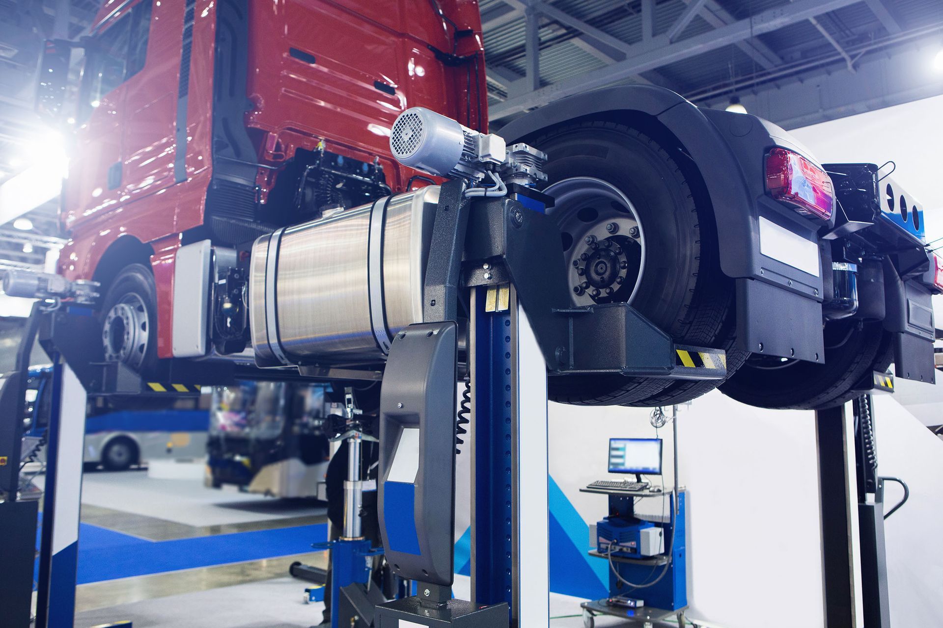 A red truck on a lift, undergoing wheel alignment in a garage.