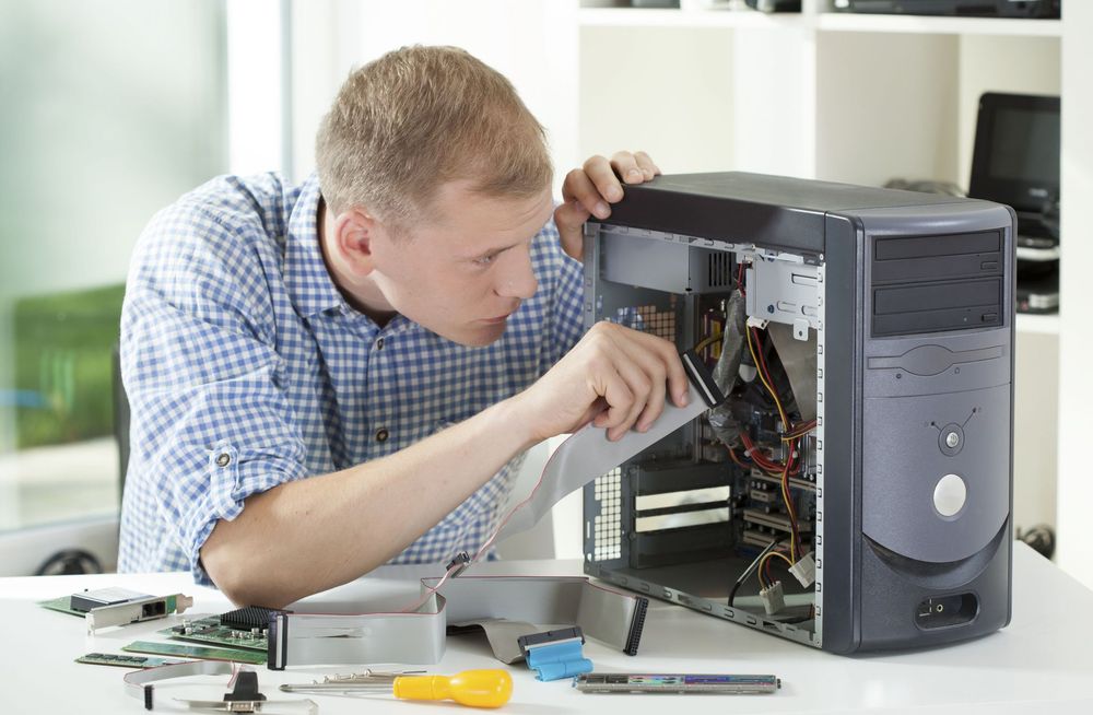 A man is working on a computer with a screwdriver.