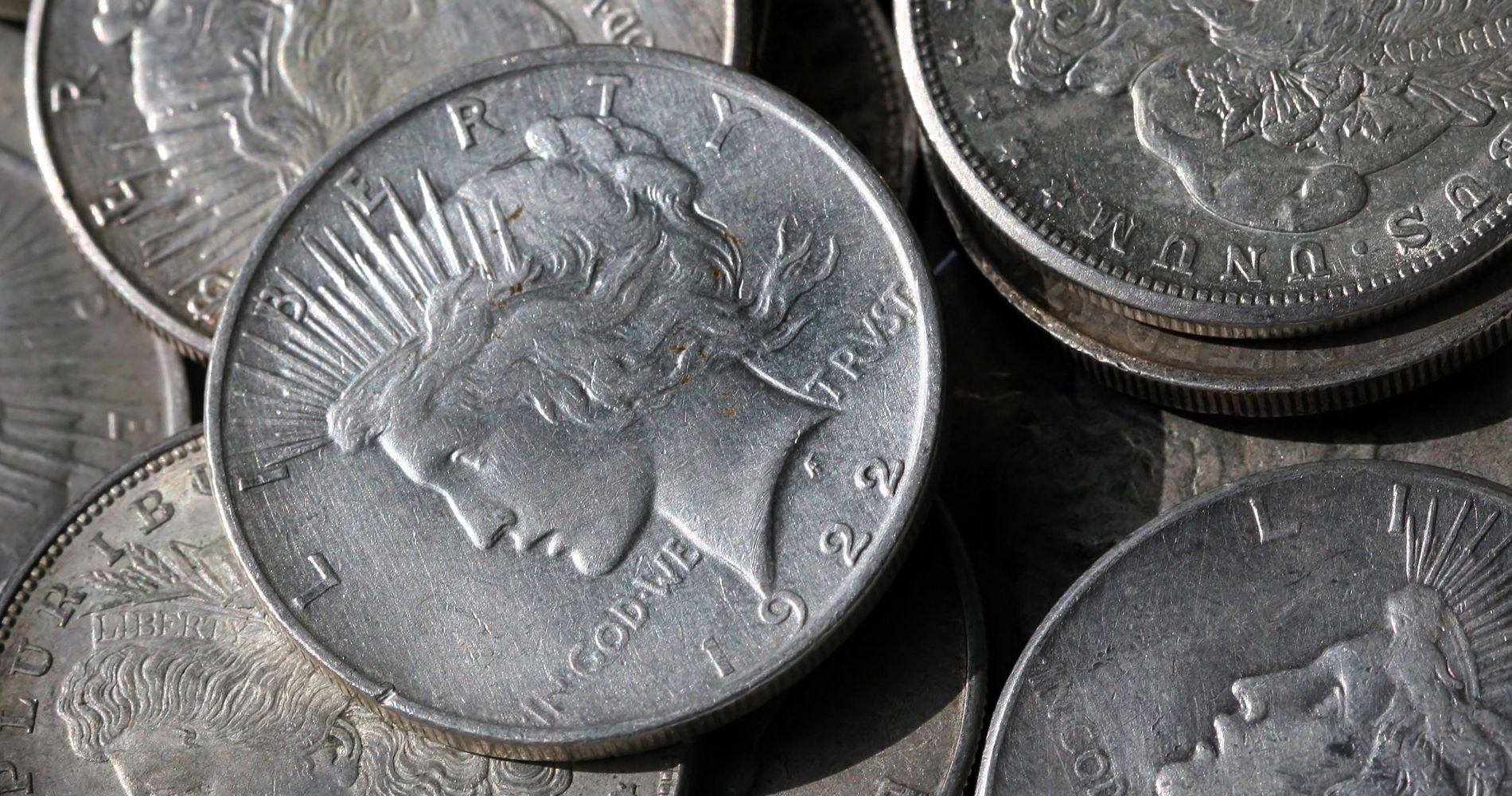 Silver Peace dollar coins, close-up, piled together.