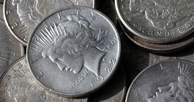 Silver Peace dollar coins, close-up, piled together.