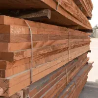 Stack of reddish-brown lumber boards bound together with white straps, likely at a lumberyard.