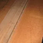 Wooden planks, some lighter in color than others, on a wood surface, with visible grain and texture.