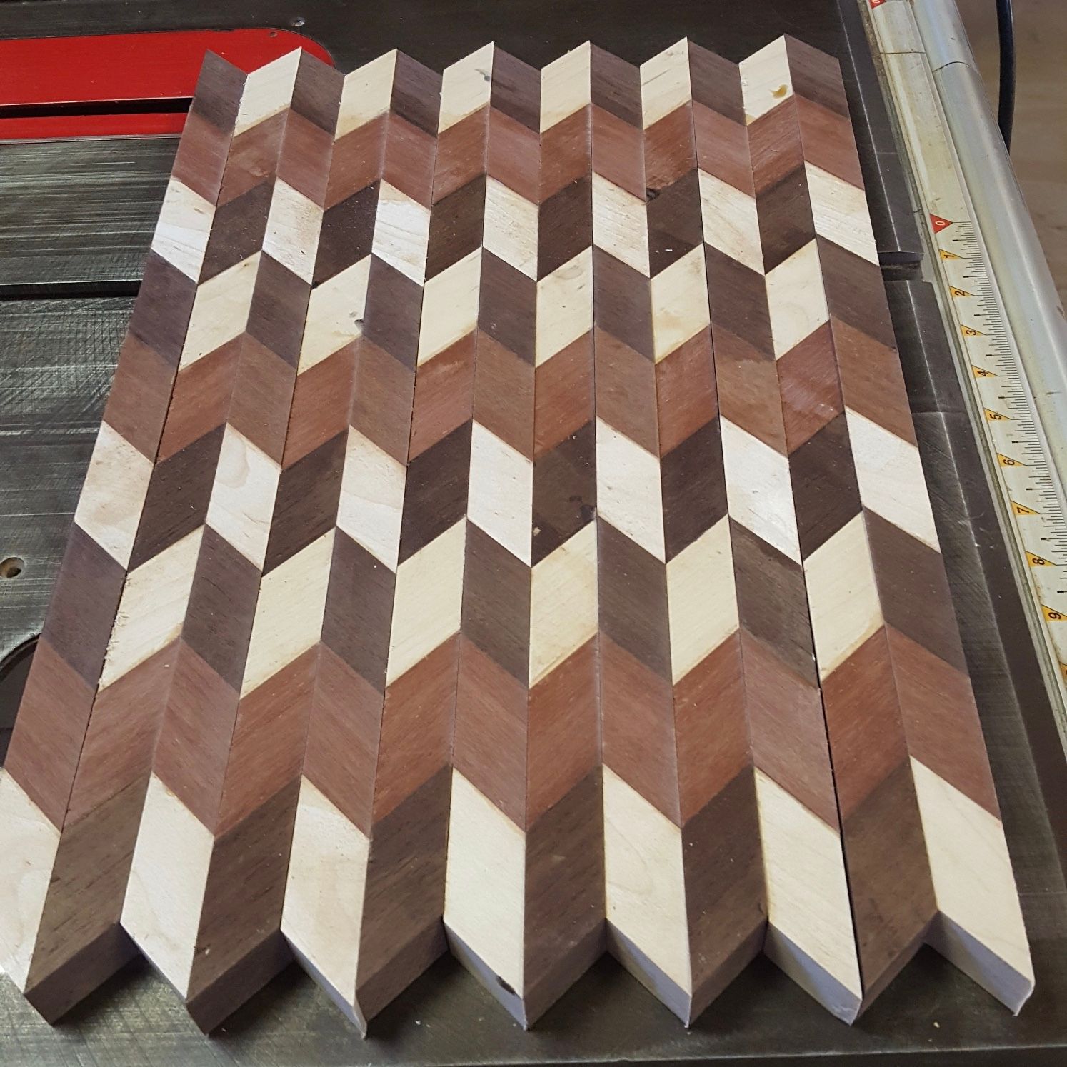 Herringbone pattern wooden surface in three alternating colors: light, medium, and dark brown.