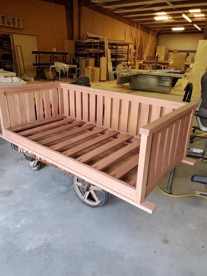 Wooden wagon bed frame with slat supports, in a workshop.