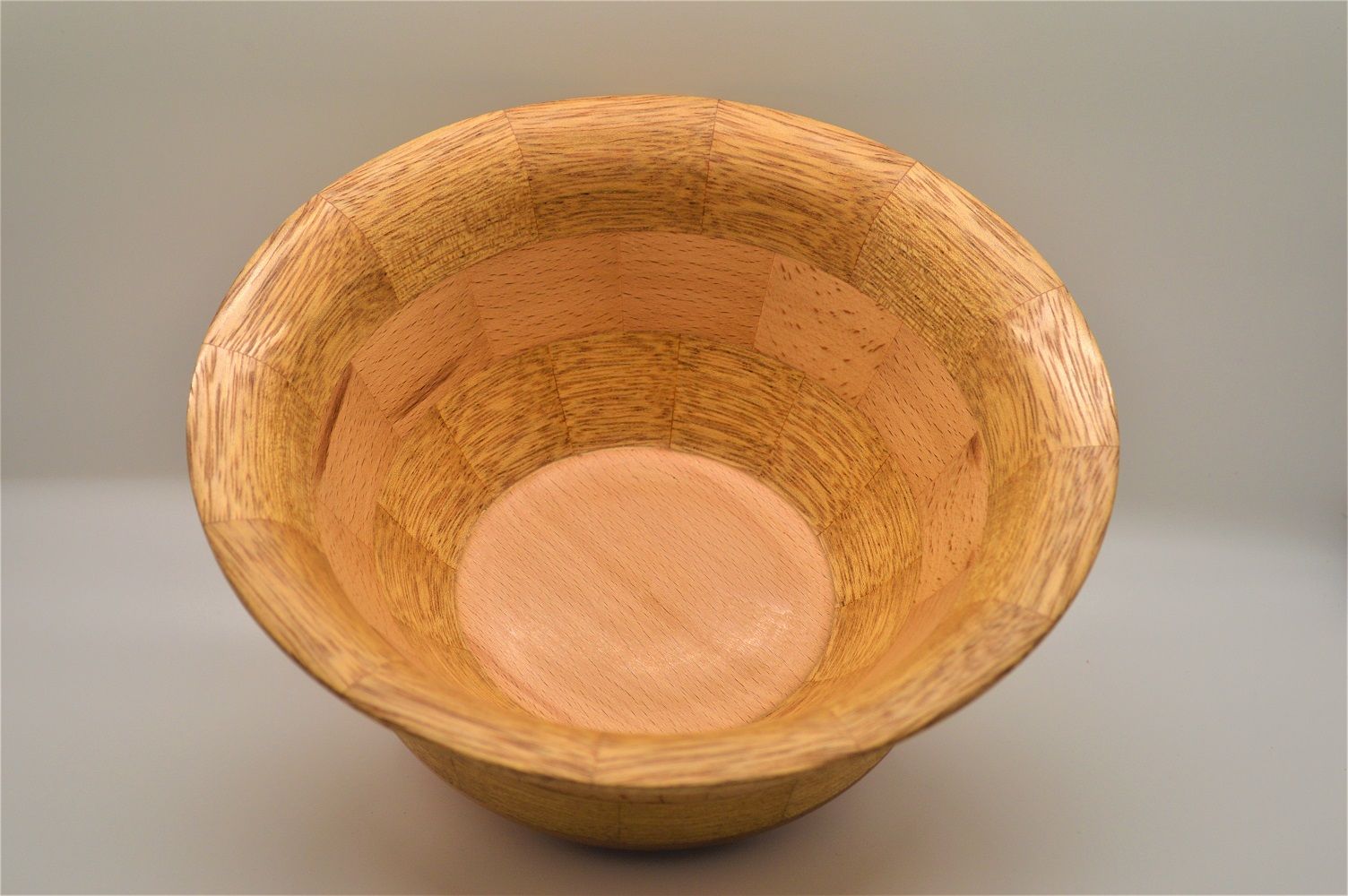Looking into a light brown wooden bowl, showing interior grain and a flat bottom.