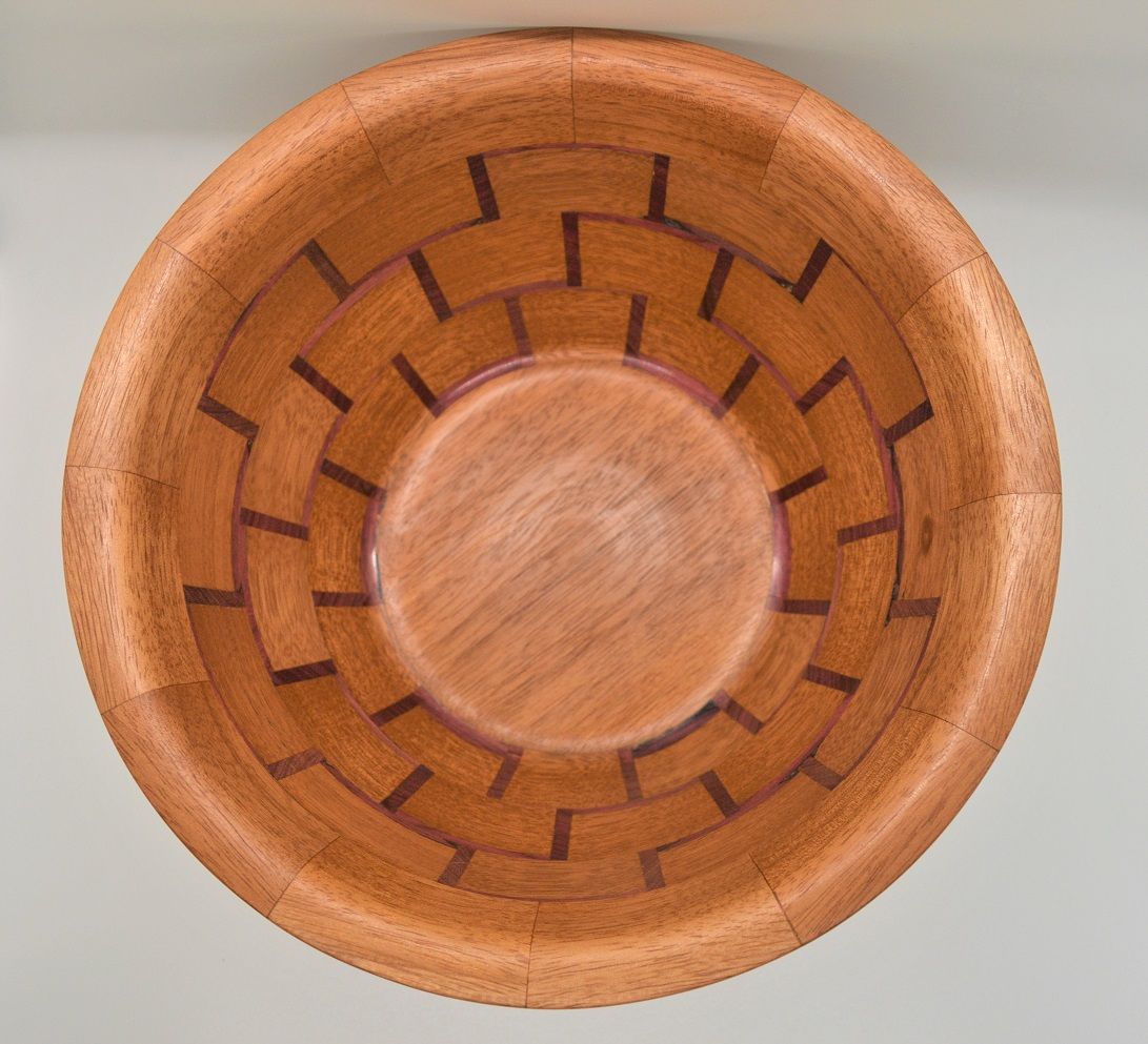 Top-down view of a wooden bowl with a patterned rim and a light-colored center.