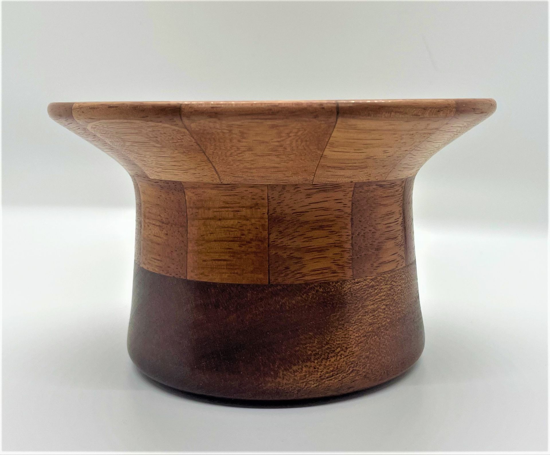 Wooden decorative bowl with a flaring top, cylinder-shaped middle, and rounded base. It has three distinct shades of brown.
