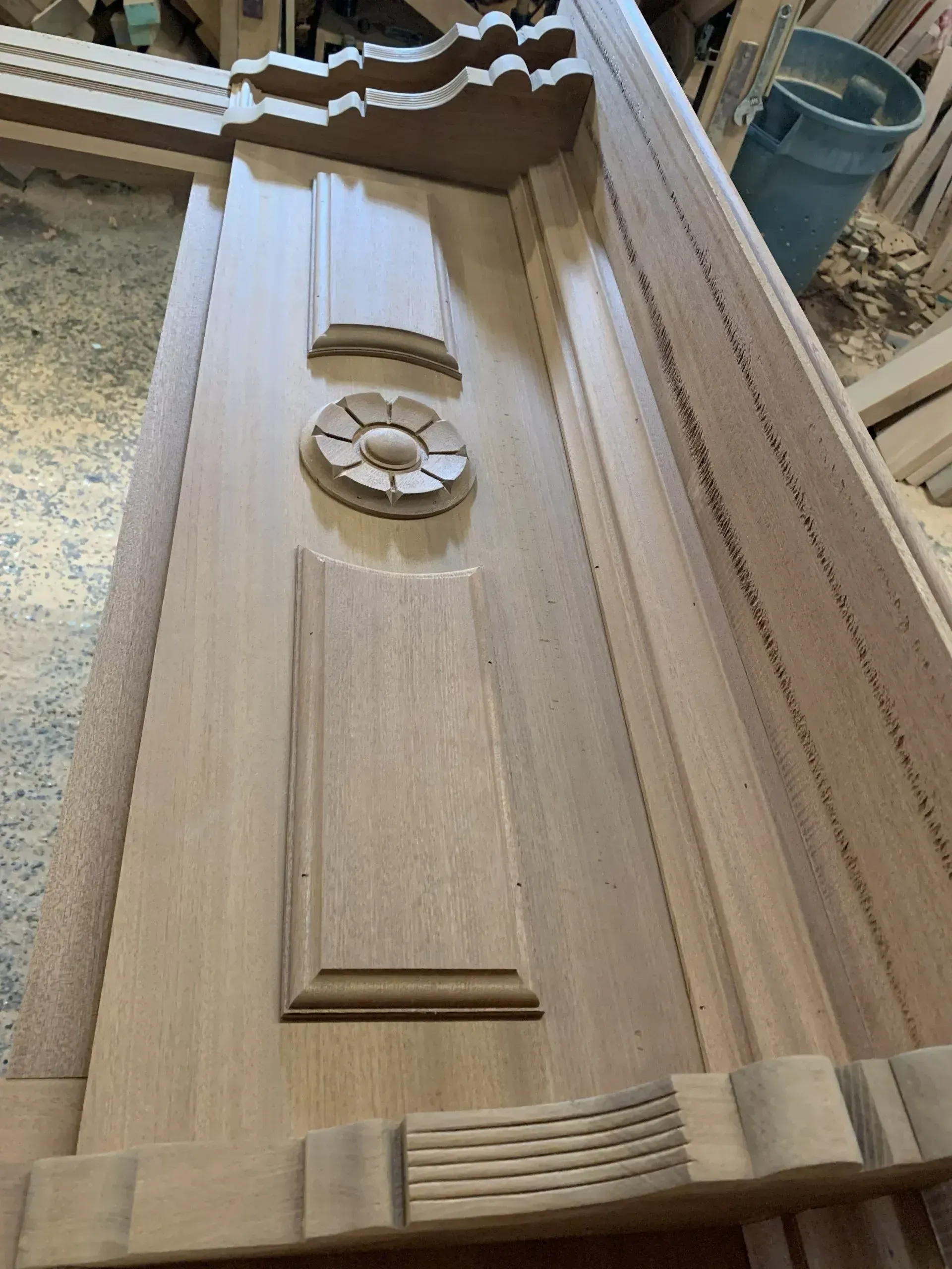 Close-up view of an unfinished wooden door frame with decorative moldings and relief carvings.