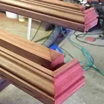Two angled wood trim pieces, one on top of the other. The wood is stained with a reddish-brown finish.