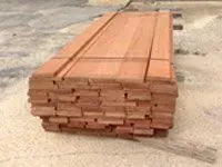 A stack of reddish-brown wooden boards bound together on a concrete surface.
