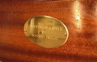 A brass plaque on a wood surface reads 