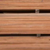 Stack of reddish-brown lumber, likely wood planks, neatly organized.