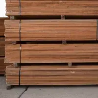 Stacks of brown lumber, secured with black straps, on a wooden pallet, likely outdoors.