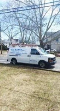 A white R.J. Kenny service van parked on a suburban street with bare trees in the background.