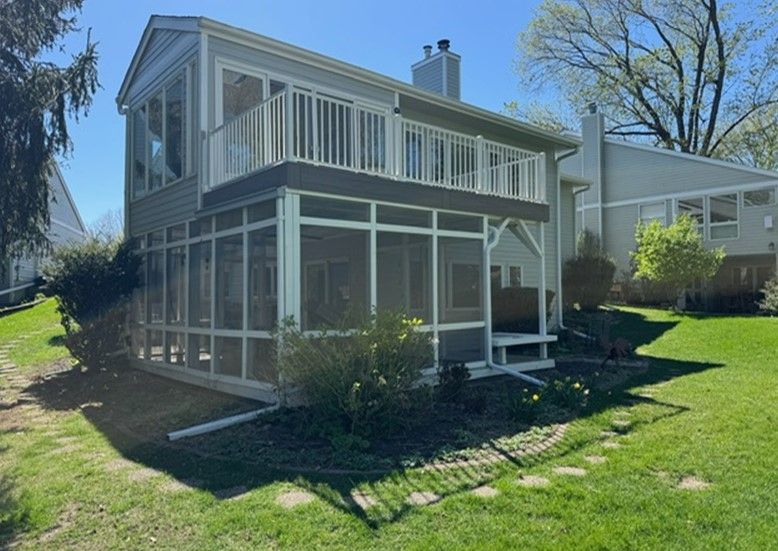 A house with a screened in porch and a large deck