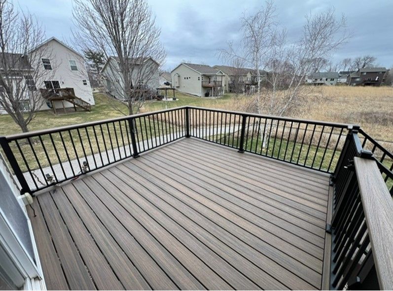 A large deck with a black railing and a view of a field.