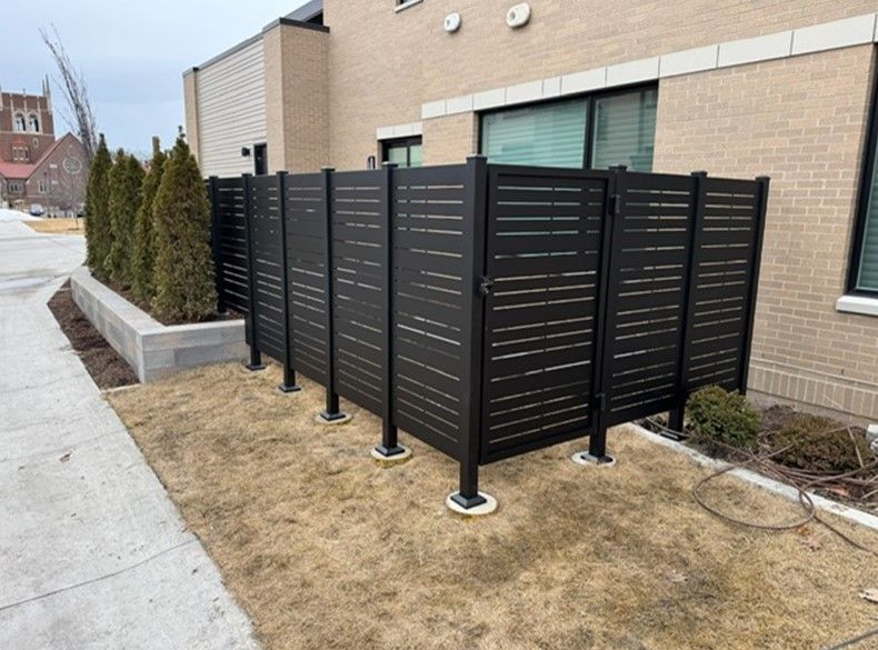 A black fence is sitting in front of a brick building.