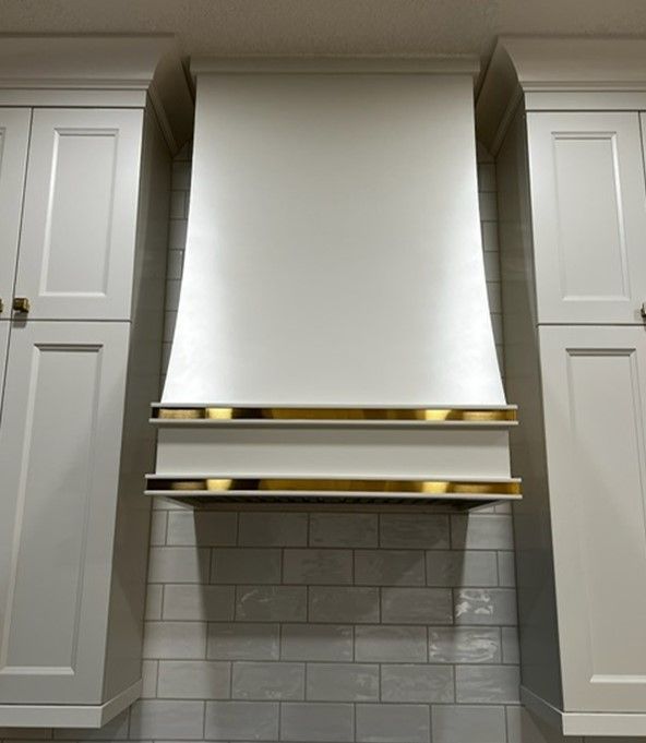 A kitchen with white cabinets and a white hood