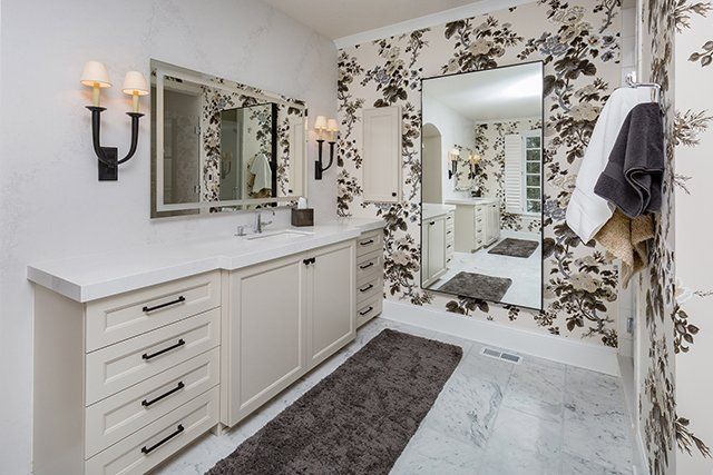 A bathroom with a large mirror and floral wallpaper.