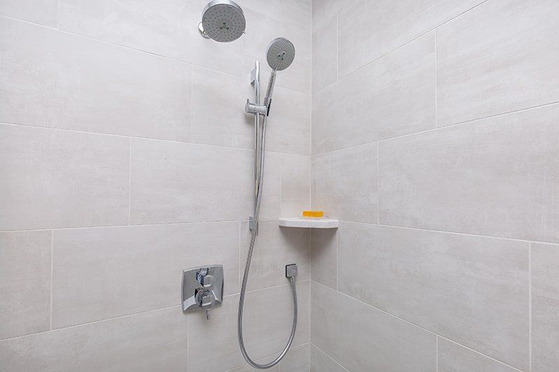 There is a shower head in the corner of the bathroom.