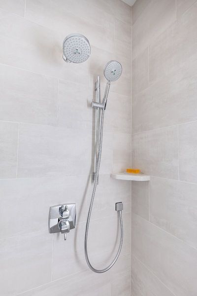 A close up of a shower head and hose in a bathroom.