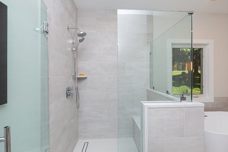 A bathroom with a walk in shower and a tub.