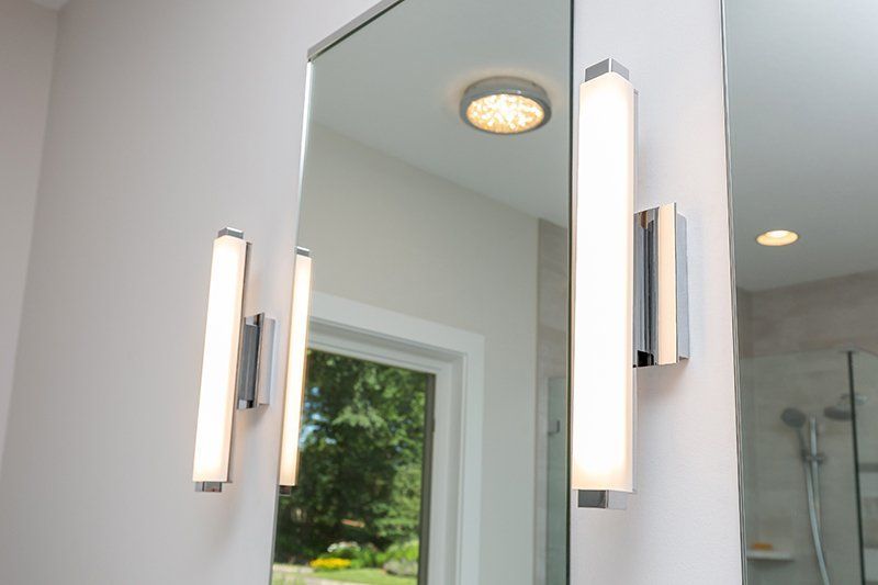 A bathroom mirror with two lights on the side of it.