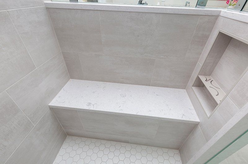 A shower with a bench and a shelf in it.