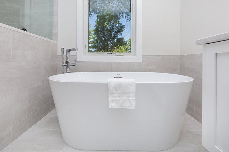 A white bathtub in a bathroom next to a window.