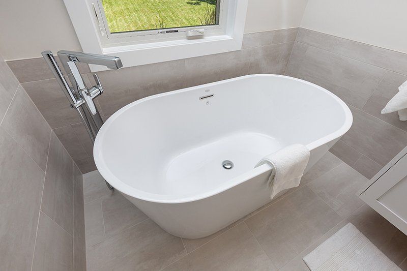 A white bathtub is sitting in a bathroom next to a window.