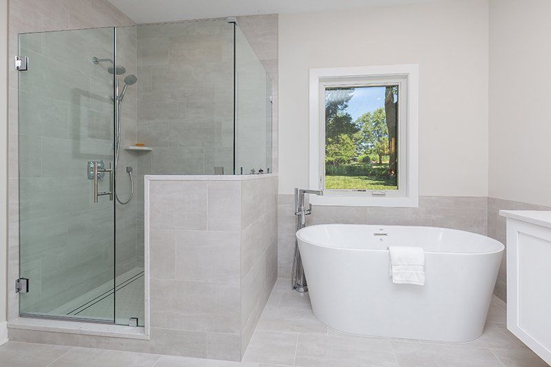 A bathroom with a tub , shower , and window.