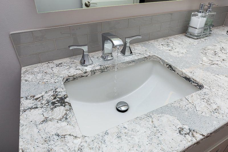 A bathroom sink with a granite counter top and a mirror.