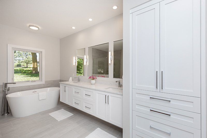 A bathroom with a tub , sink , mirror and cabinets.