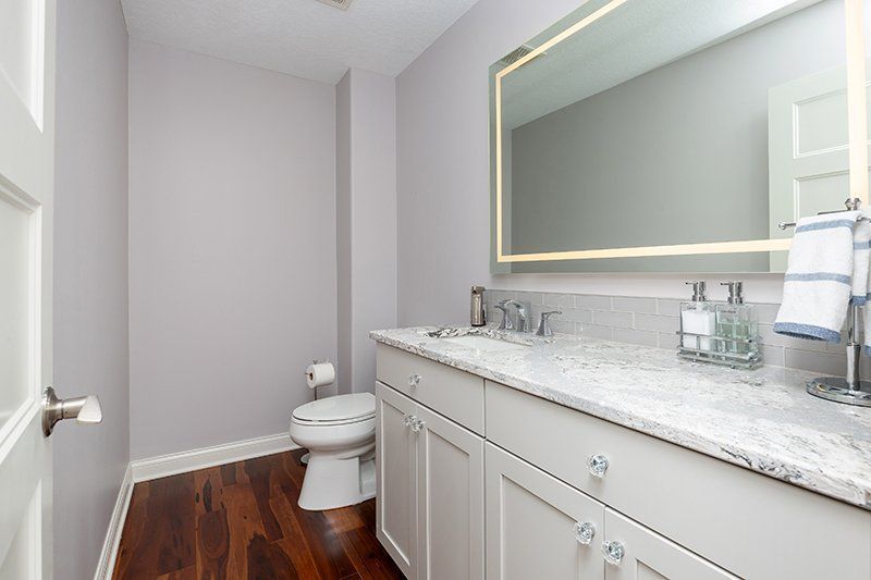 A bathroom with a toilet , sink and mirror.