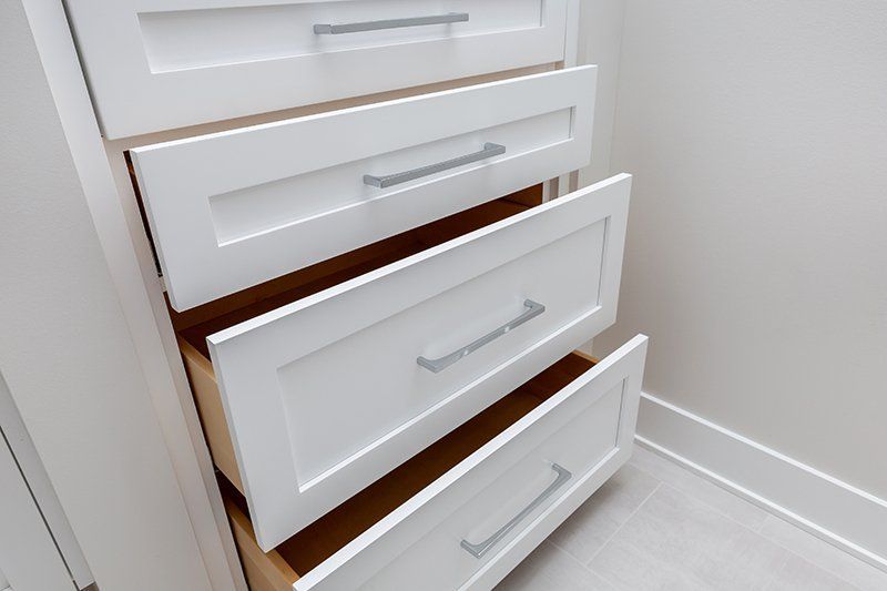 A white dresser with the drawers open in a bathroom.