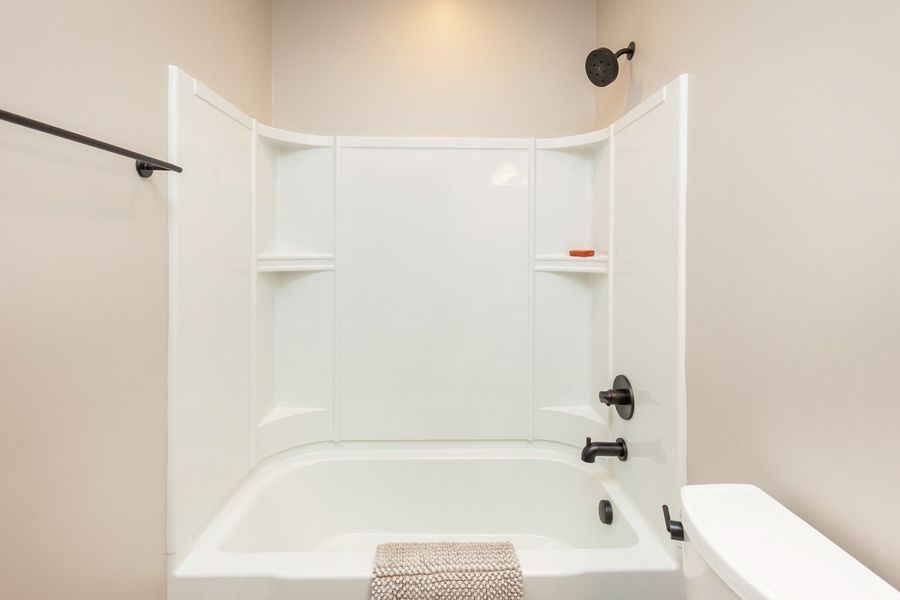 A bathroom with a bathtub , toilet and shower.