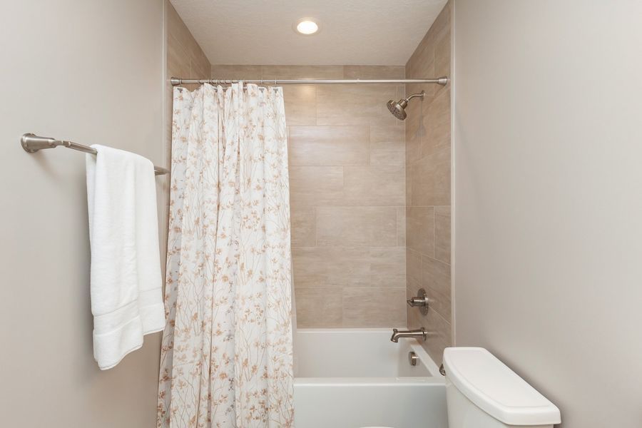 A bathroom with a bathtub , toilet and shower curtain